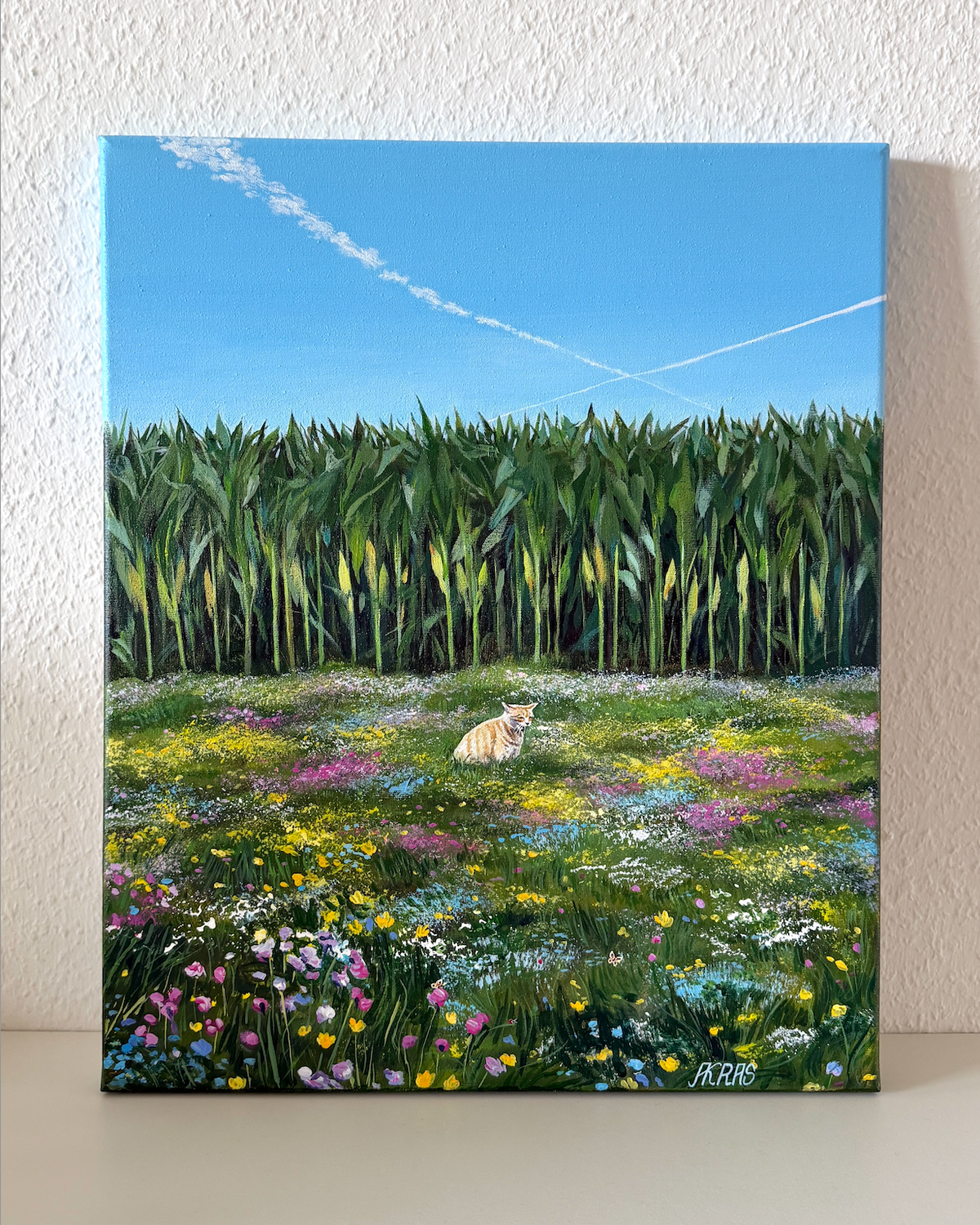 Painting of a cat sitting in a field with flowers and corn stalks.